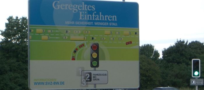 Auf einem Schild wird 'Geregeltes Einfahren' anhand einer skizzierten Verkehrssituation an ZRA aus der Vogelperspektive veranschaulicht.